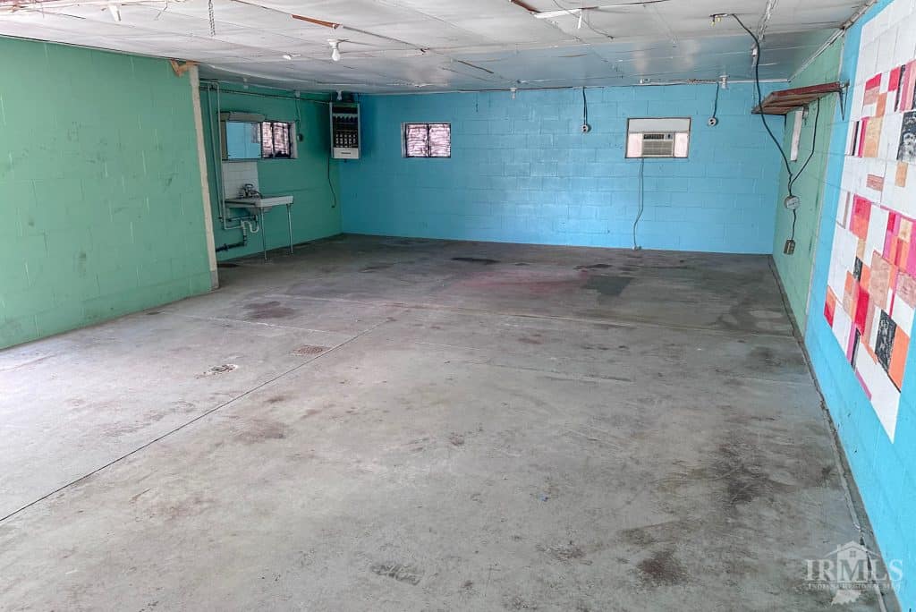 Clean, spacious garage with colorful painted walls and concrete floor in Muncie, Indiana. Ideal for storage or maintenance.