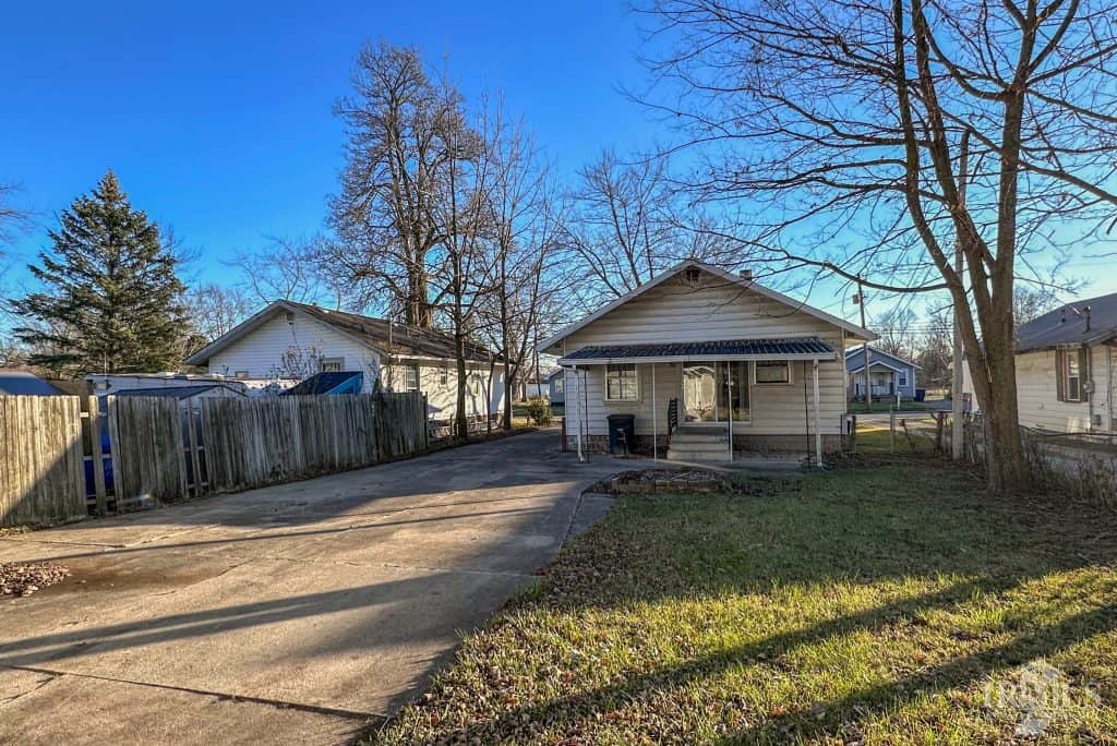 House with driveway in Muncie, Indiana, featuring a cozy front porch and mature trees.